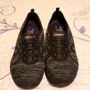 Black and grey Sketchers flats.